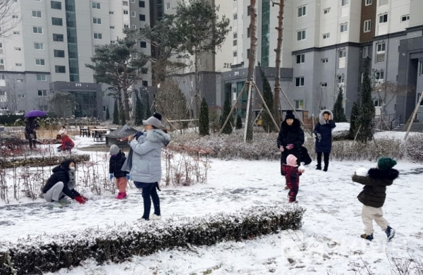 예고 없이 내린 눈에 아이가 있는 아파트 주민들이 집 밖으로 나와 눈사람을 만들고 있다.
