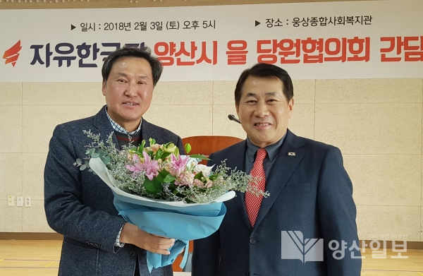 나동연  신임위원장이 이장권 전임 위원장에게 꽃다발을 건네고 있다.