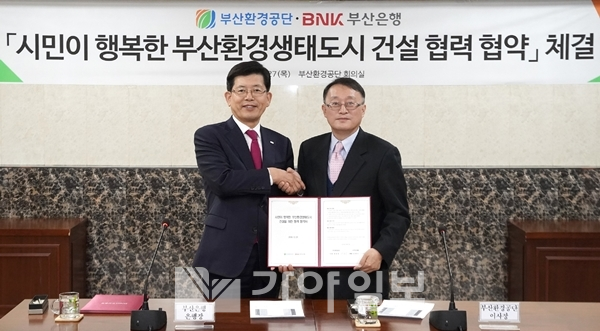 BNK부산은행 빈대인(왼쪽) 은행장이 지난 27일 부산환경공단 회의실에서 부산환경공단 배광효 이사장과 "시민이 행복한 부산환경생태도시 건설을 위해 상호 협력하기 위한" 협약서를 들어보이며 악수하고 있다.(사진제공=부산은행)